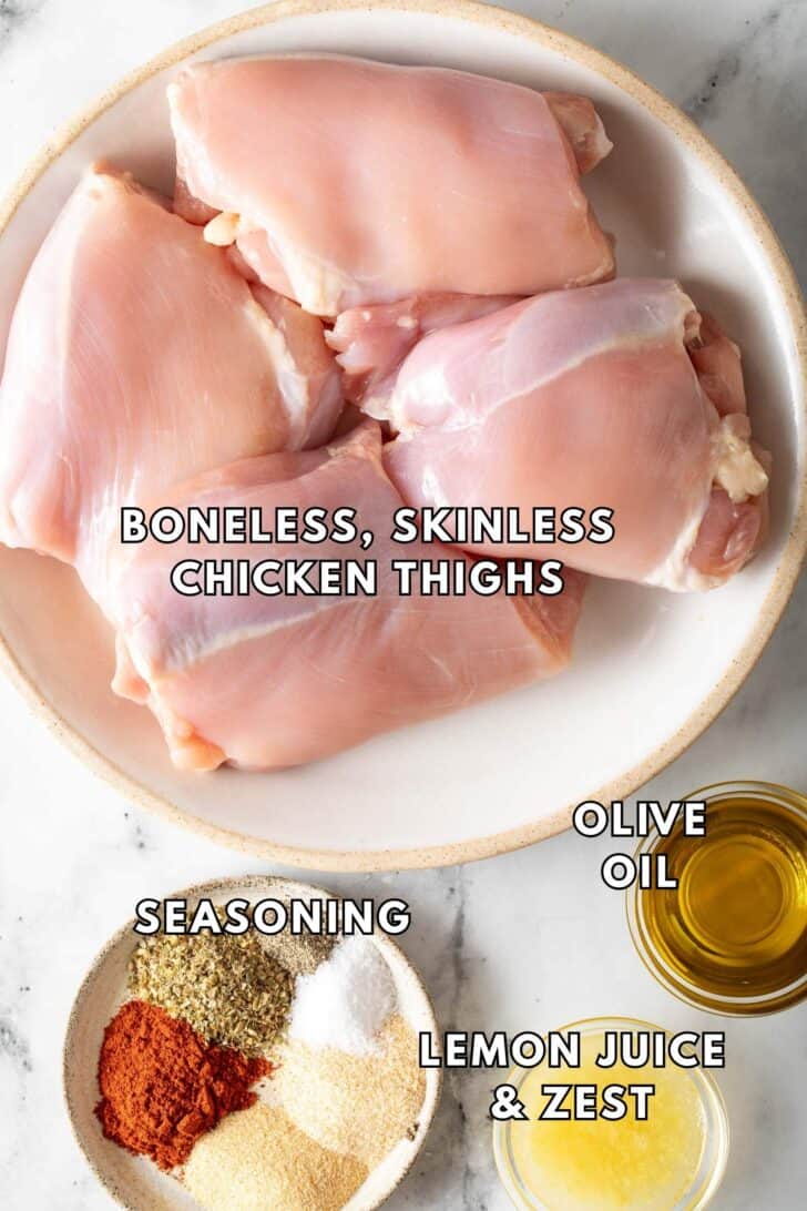 Baked Boneless Skinless Chicken Thighs Recipe Boneless Chicken Thighs on a white plate next to a dish of seasonings.