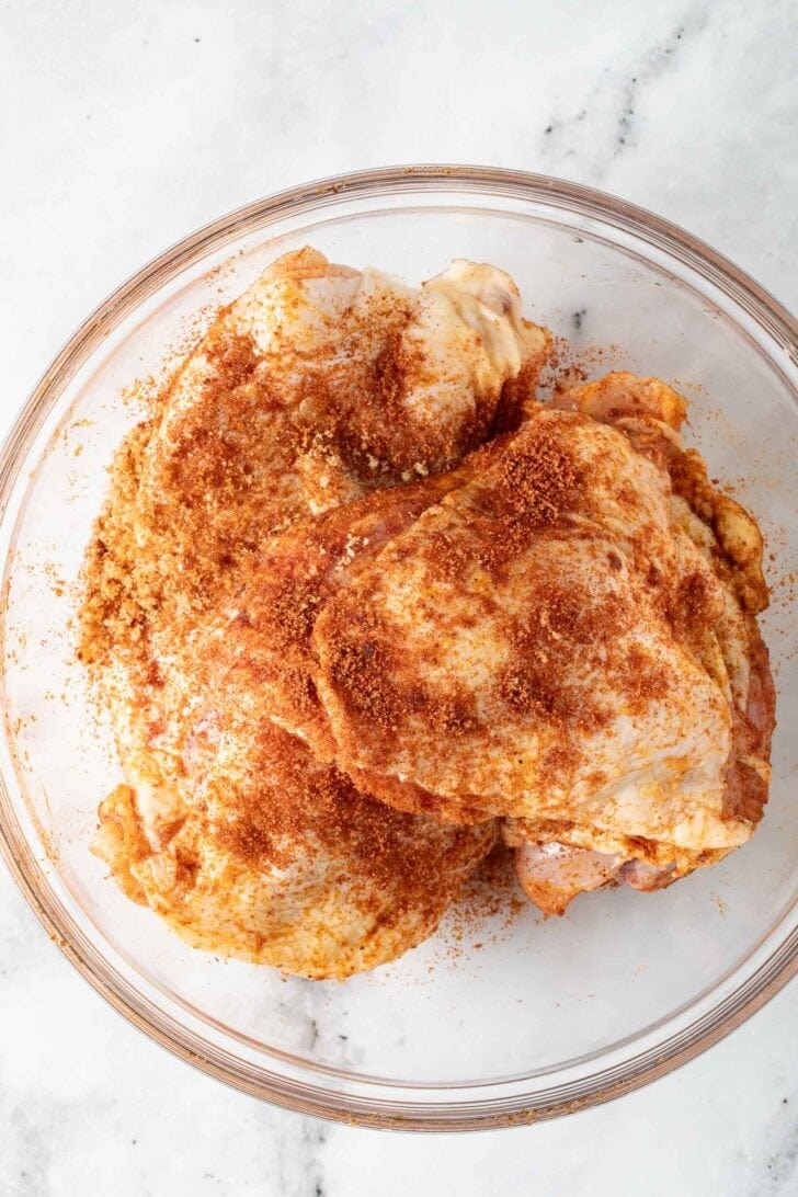 Baked Barbecue Chicken Thighs Recipe Chicken thighs with seasoning in a glass bowl.