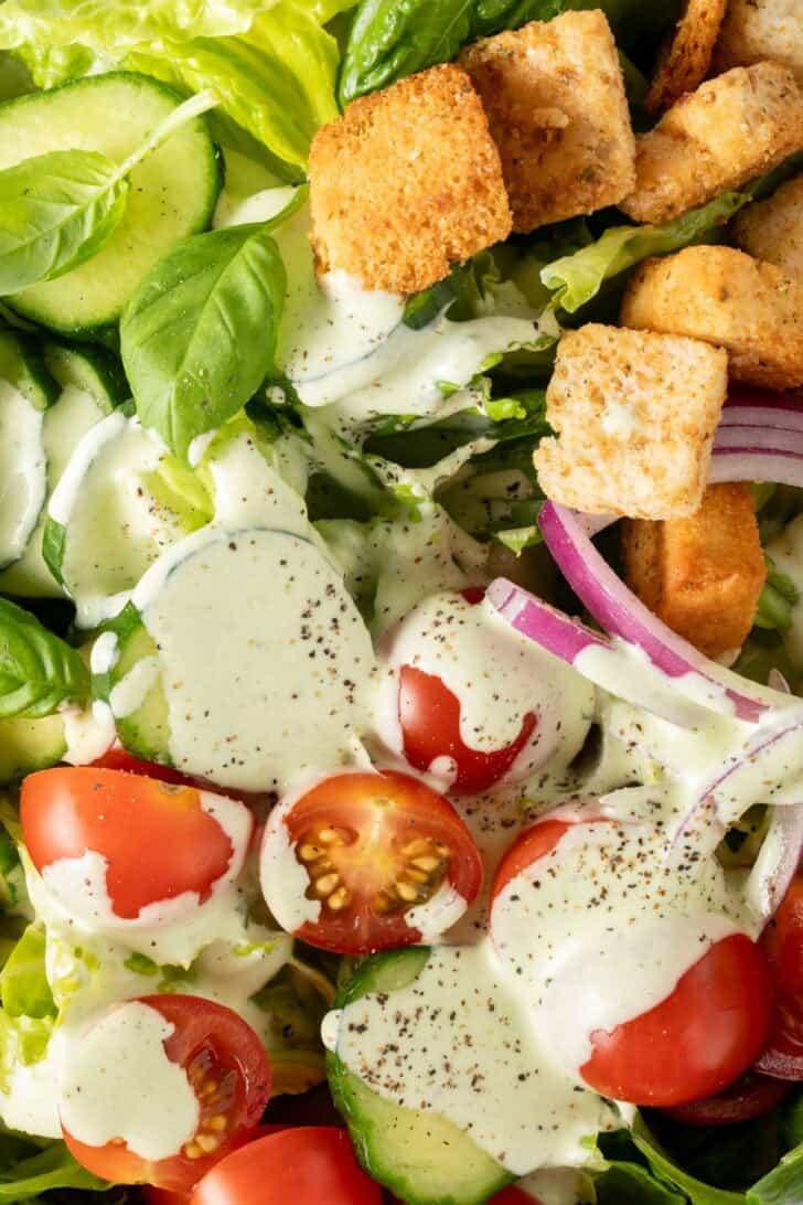 Pesto Ranch Salad Dressing tossed with salad in a bowl.