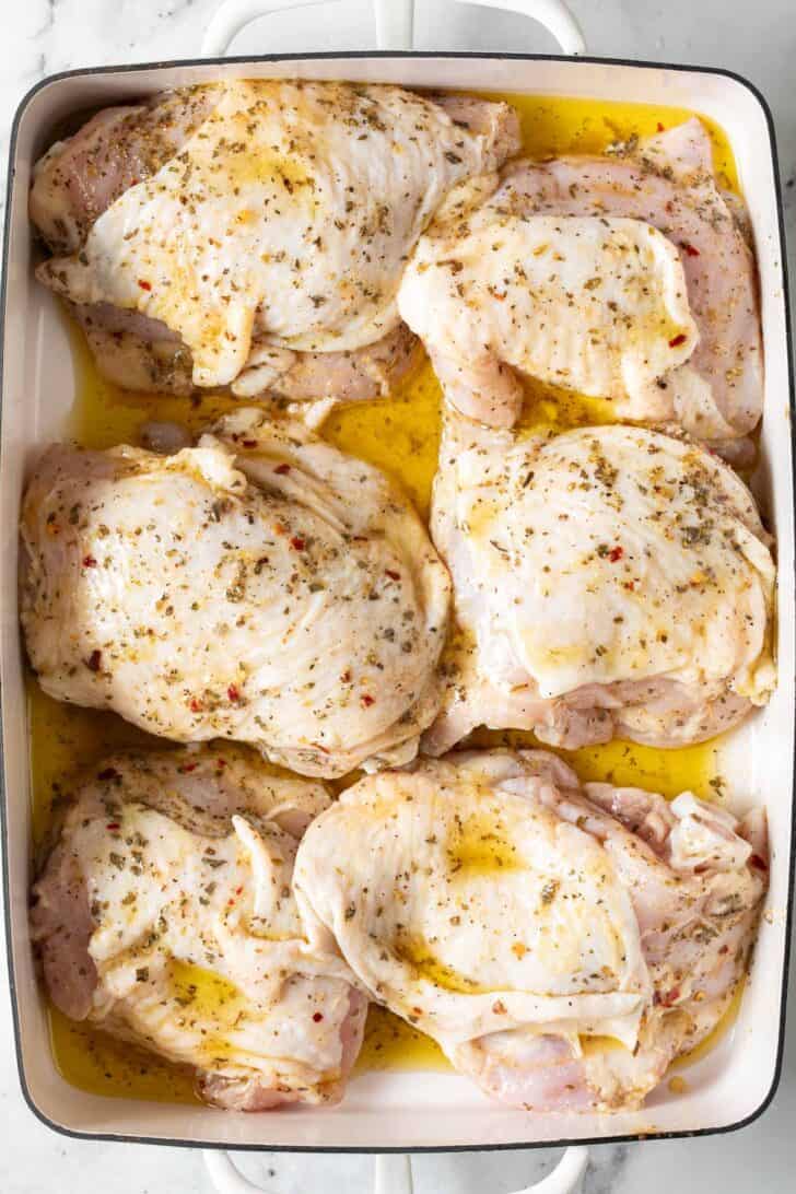 Chicken Marinated in Italian Dressing Marinated chicken in a white baking pan.