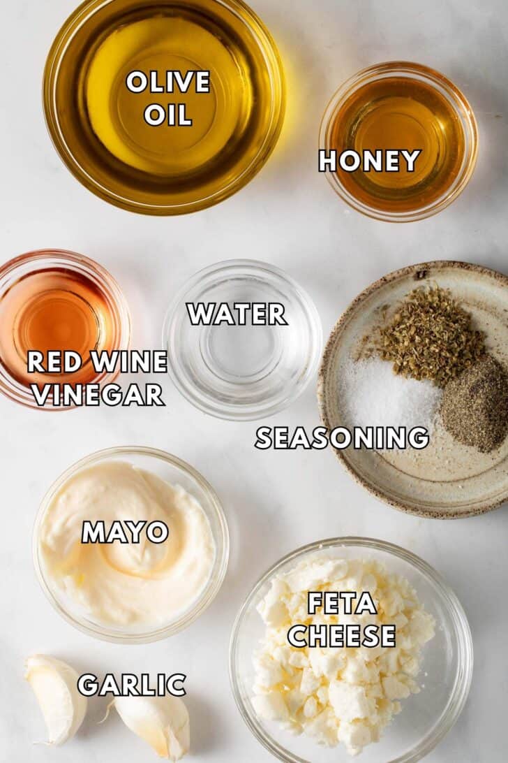 Creamy Greek Salad Dressing Recipe Clear glass bowls filled with olive oil, red wine vinegar, mayonnaise, feta cheese and honey for a Creamy Greek Salad Dressing recipe.