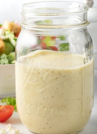 Creamy Greek Salad Dressing in a clear glass mason jar.