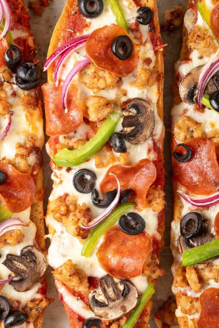 Garlic Bread Pizza Garlic bread pizza with pepperoni, Italian sausage, mushrooms and onions on a baking sheet.