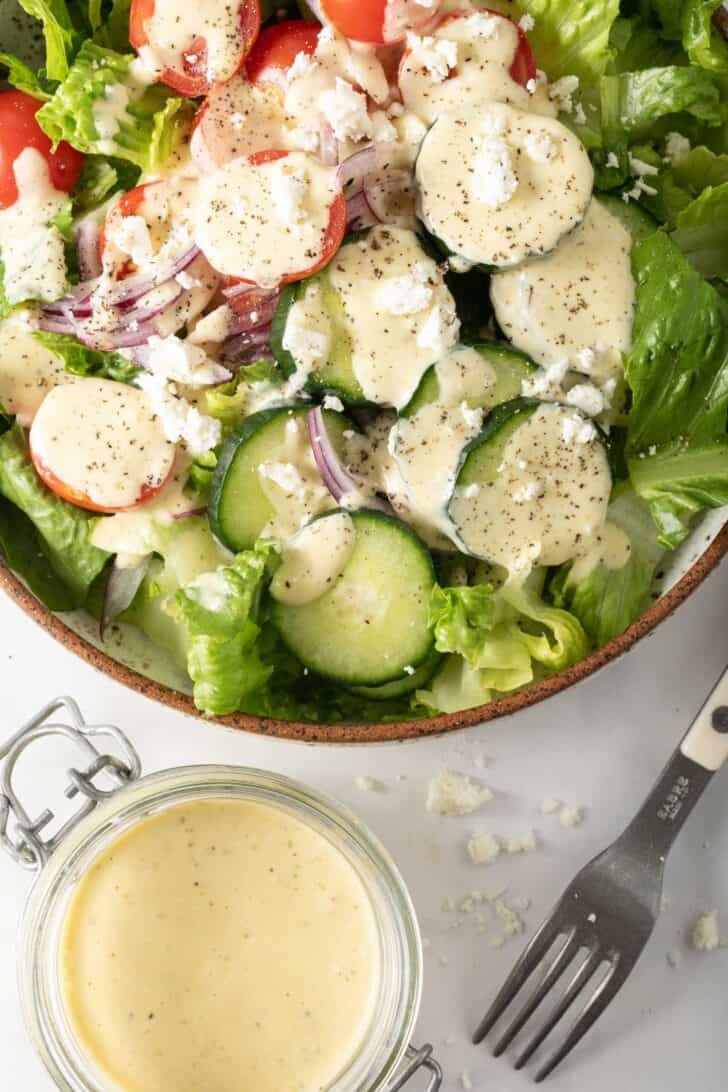 Greek Feta Dressing Greek Feta Dressing tossed with a salad in a bowl.