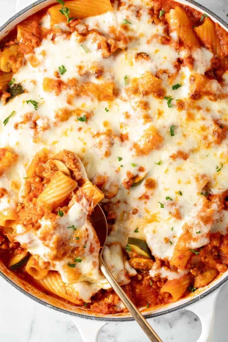 Pasta with Ground Turkey Pasta with Ground Turkey and vegetables in a white skillet with melted cheese.