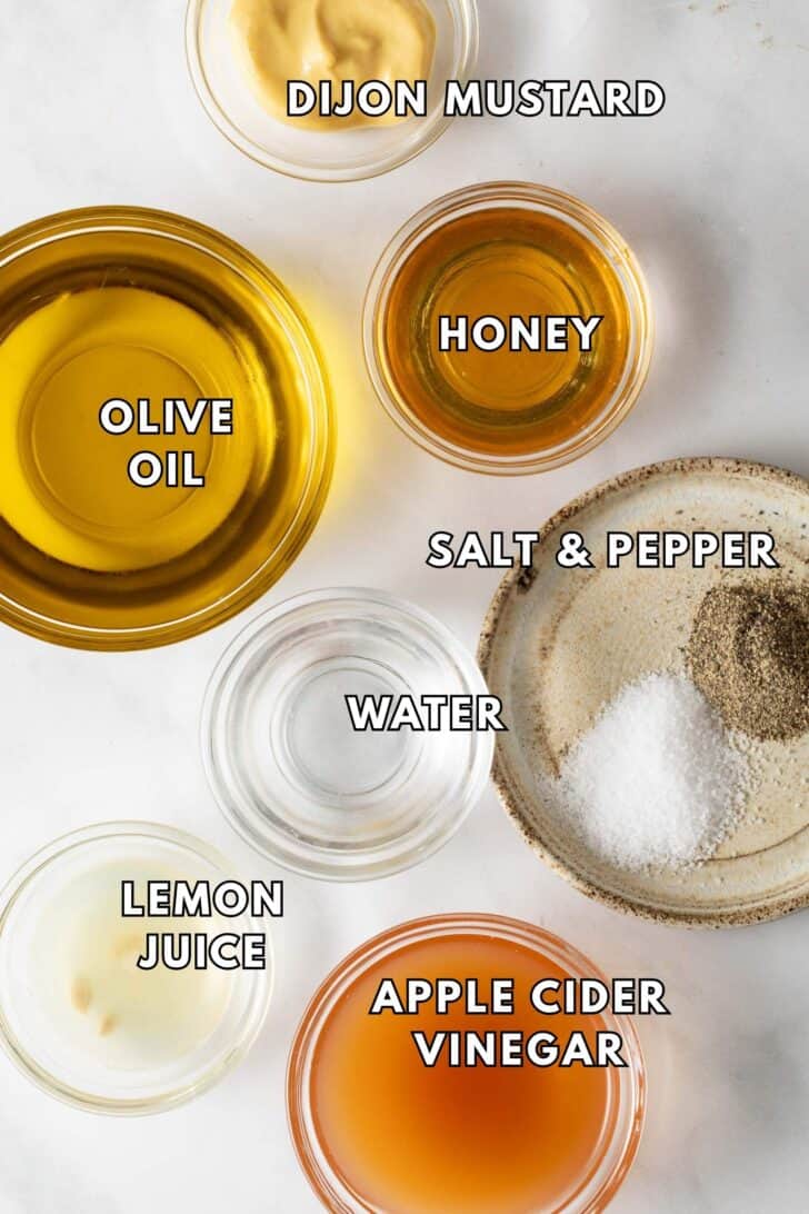 Honey Vinaigrette Recipe Clear glass bowls filled with olive oil, honey, Dijon mustard and apple cider vinegar for a honey vinaigrette recipe.