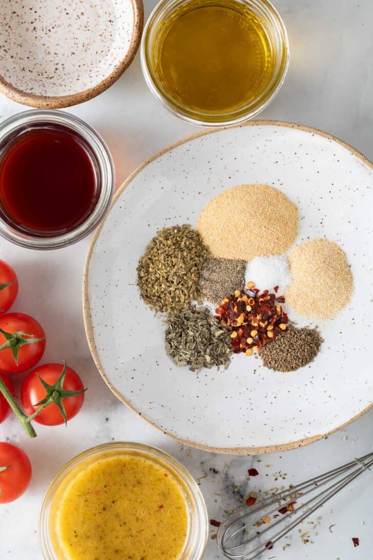 Italian Salad Dressing Mix Italian Salad Dressing Mix ingredients on a white dish next to small glass bowls of olive oil and red wine vinegar.