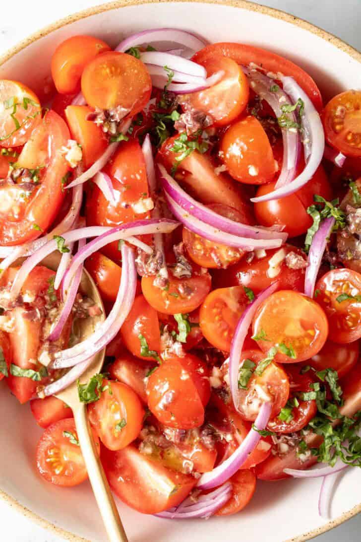 Tomato and Red Onion Salad A tomato and red onion salad in a white bowl.