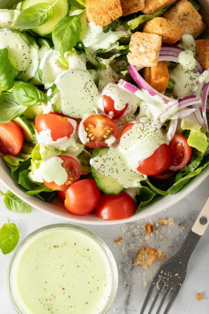 Creamy Pesto Ranch Dressing toss on a salad in a bowl.