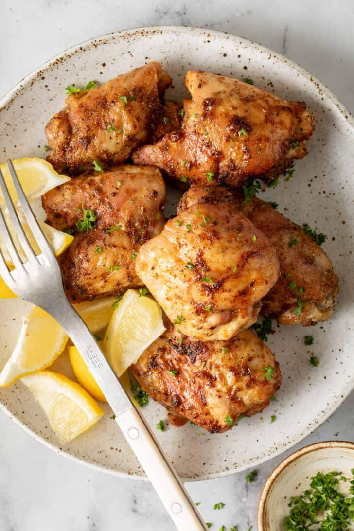 Air Fryer Chicken Thighs Air Fryer Chicken Thighs on a plate with lemon wedges.