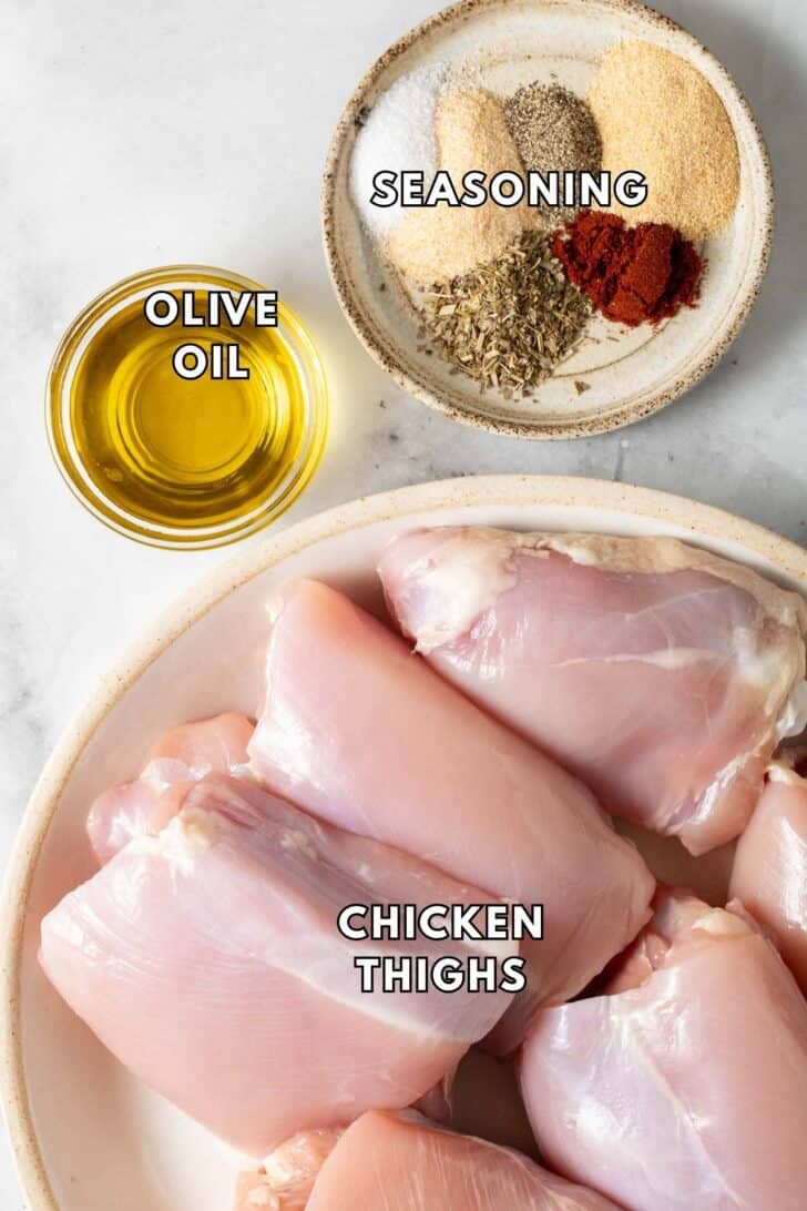Air Fryer Chicken Thighs Recipe Boneless skinless chicken thighs on a plate next to a dish of seasoning.