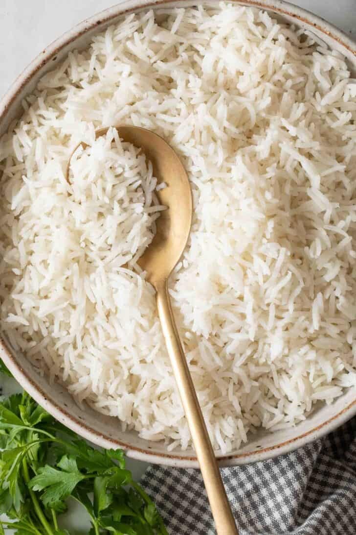 Cooking Basmati Rice On Stove Fluffy Basmati Rice in a bowl with a serving spoon.