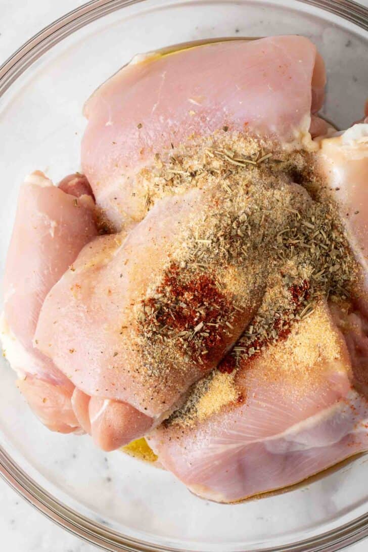Boneless Skinless Chicken Thighs in Air Fryer Boneless Skinless Chicken Thighs with olive oil and seasoning in a clear glass mixing bowl.