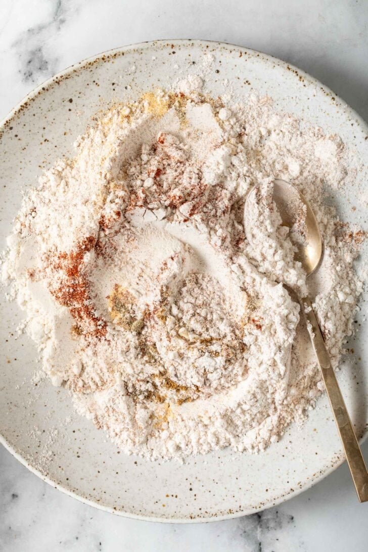 Crispy Chicken Tacos Recipe Seasoned white flour in a dish with a spoon.