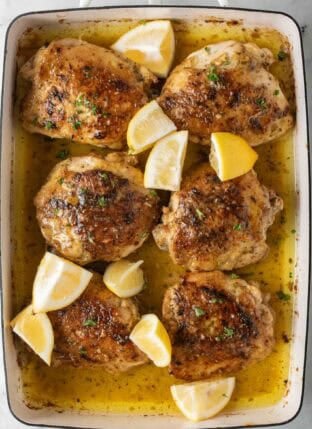 Greek Lemon Chicken in a white roasting pan.
