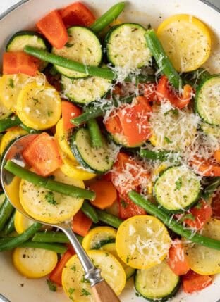 Sautéed vegetables in a white skillet.
