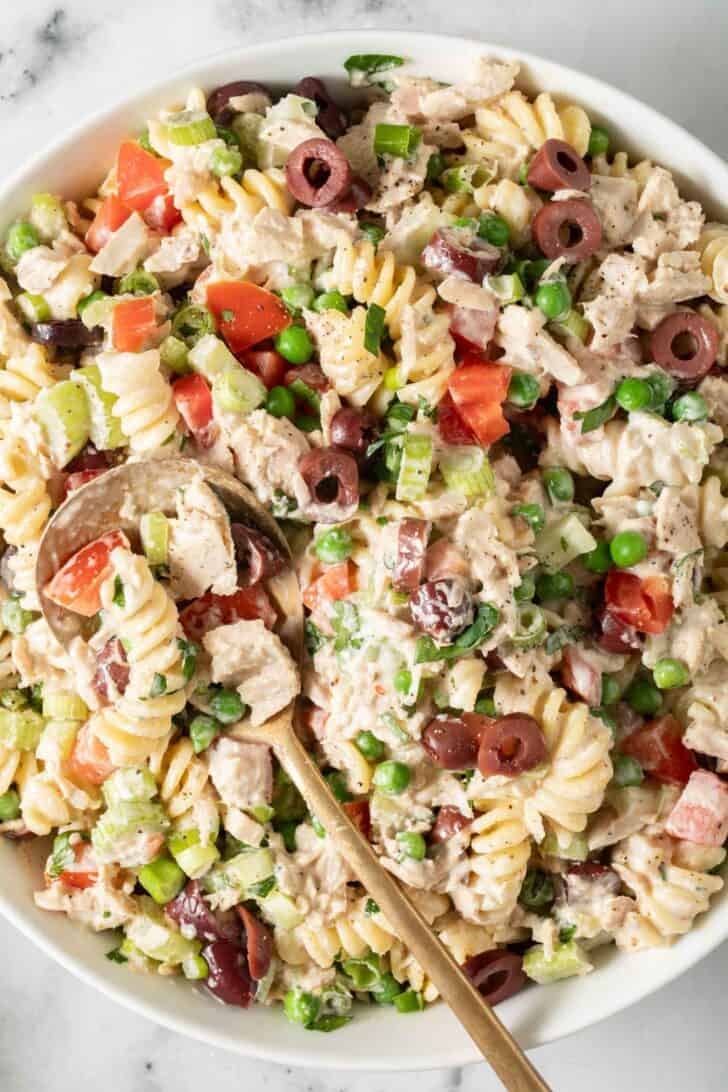 Tuna Pasta Salad Tuna Pasta Salad in a white bowl with a gold serving spoon.