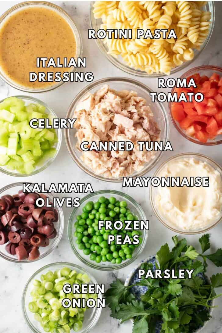 Tuna Pasta Salad Recipe Small glass bowls filled with canned tuna, frozen peas, kalamata olives, green onions and rotini pasta for a tuna pasta salad recipe.