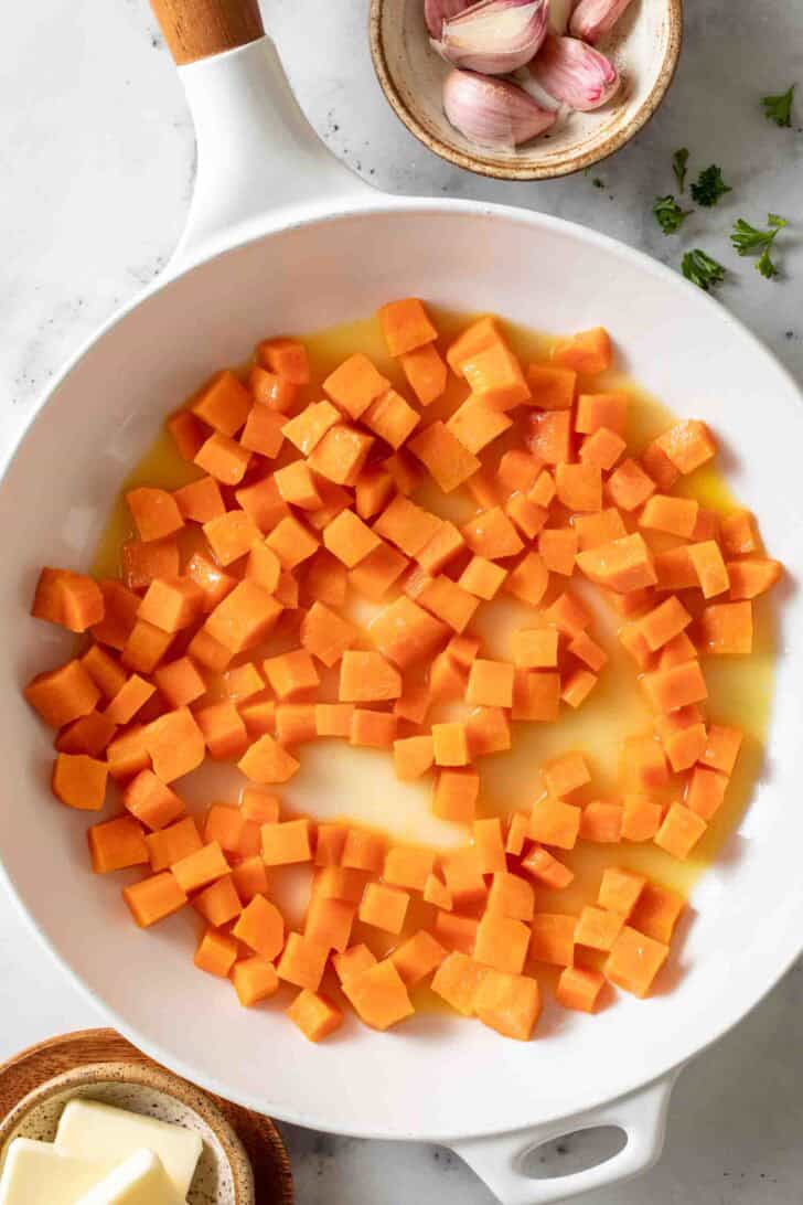 Peas and Carrots Recipe Diced carrots in a white skillet for peas and carrots.
