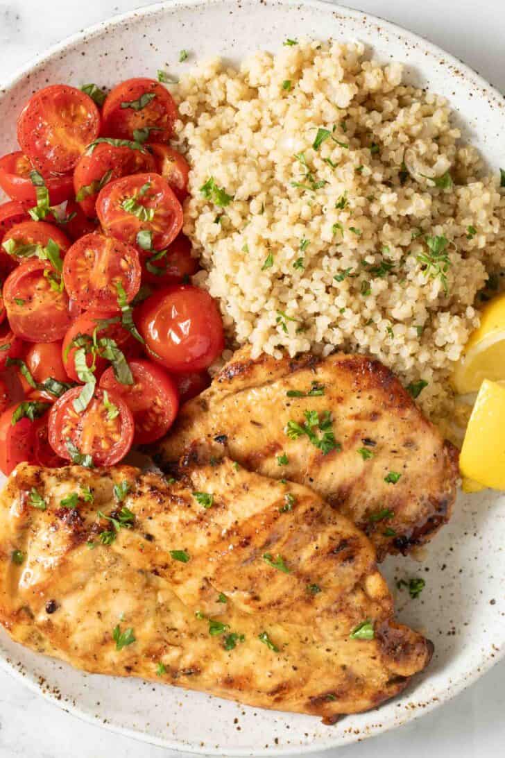 How to Make Good Tasting Quinoa Seasoned quinoa on a plate with roasted tomatoes and grilled chicken.