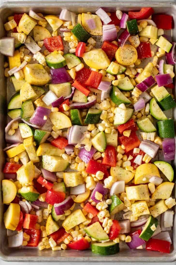 Summer Roasted Vegetables Chopped vegetables and corn kernels on a baking sheet.