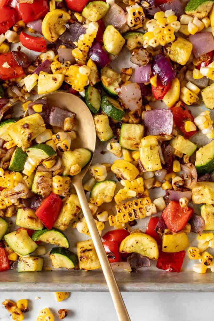 Summer Roasted Vegetables Summer Roasted Vegetables on a sheet pan with a serving spoon.