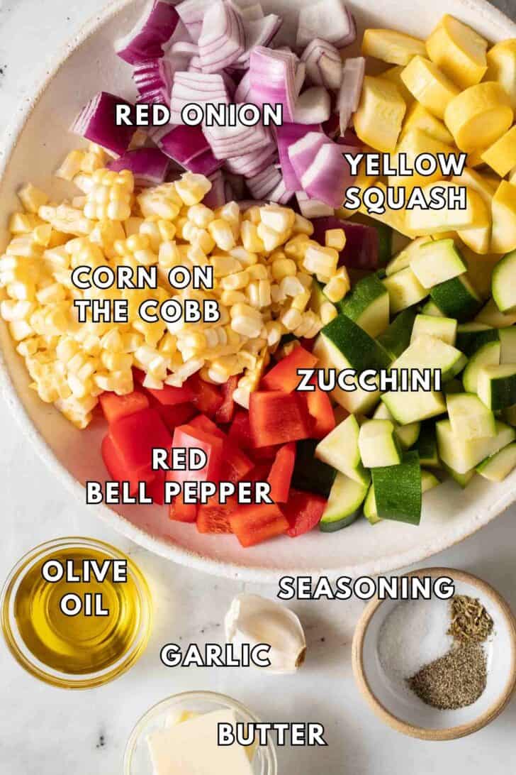 Summer Vegetables Recipe Chopped zucchini, yellow squash, red onion and red pepper in a bowl with corn.