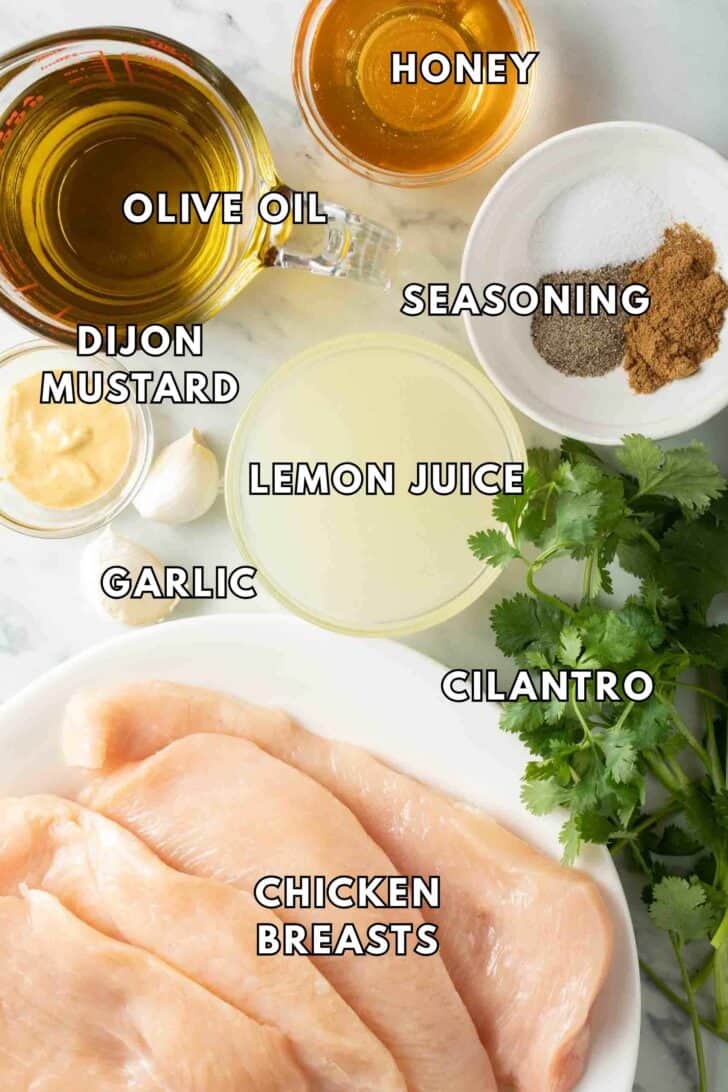 Cilantro Lime Chicken Recipe Raw chicken breasts on a white plate next to bowls of olive oil, lemon juice, honey and seasoning.