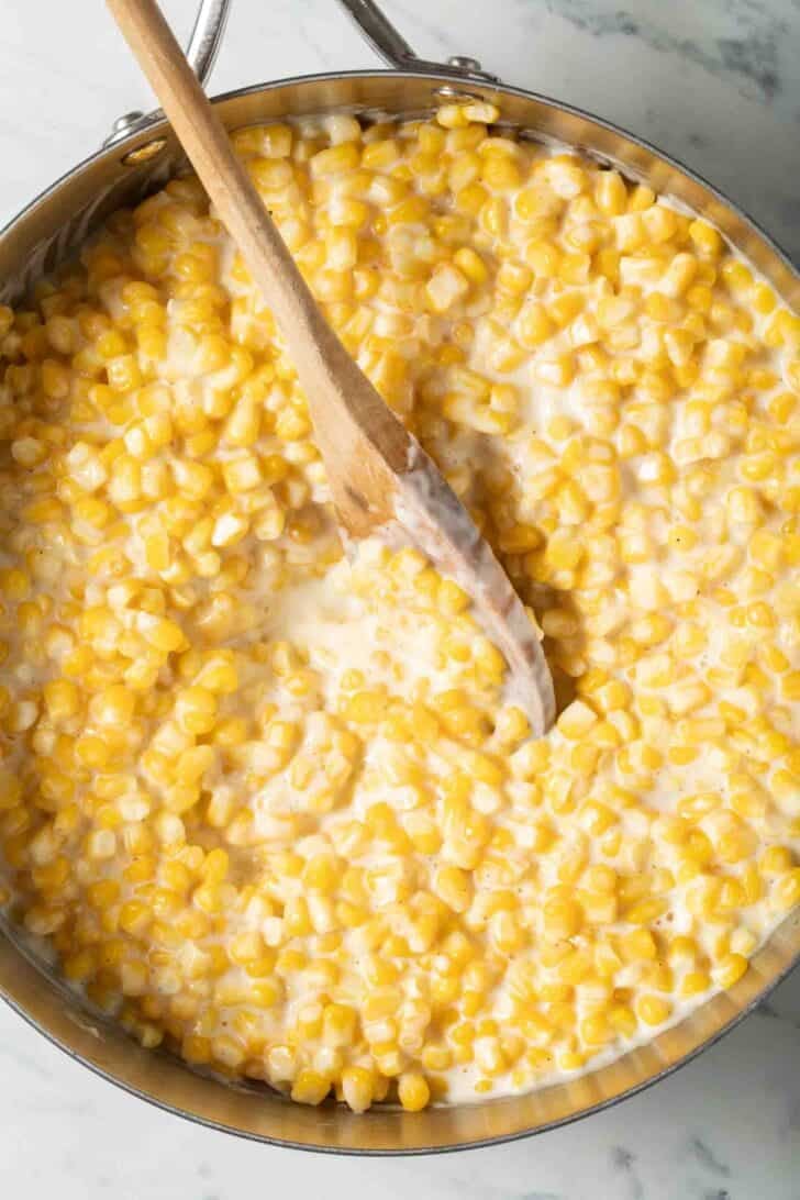 Corn and Cream Corn and cream in a skillet with a wooden spoon.