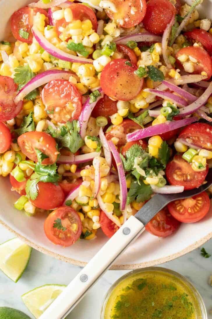 Tomato Corn Salad Tomato Corn Salad in a bowl with a serving spoon.