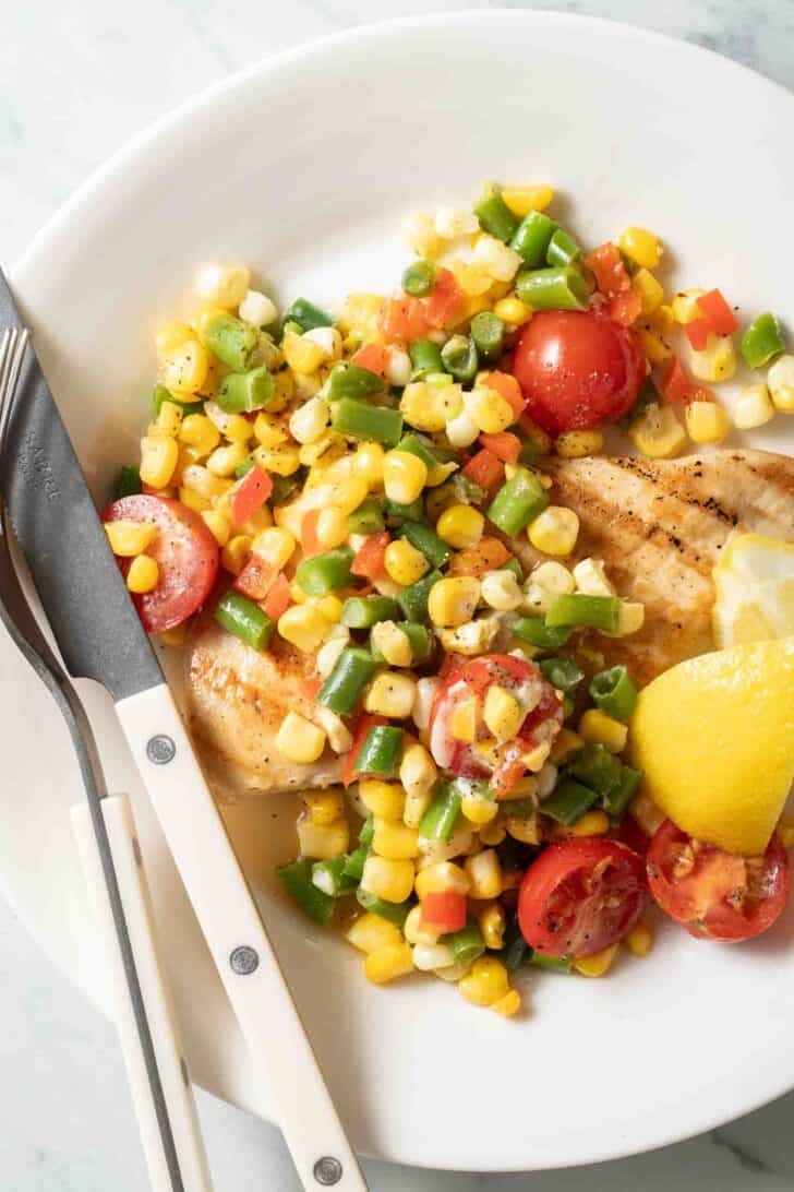 Succotash Recipe Succotash on a plate with grilled chicken.
