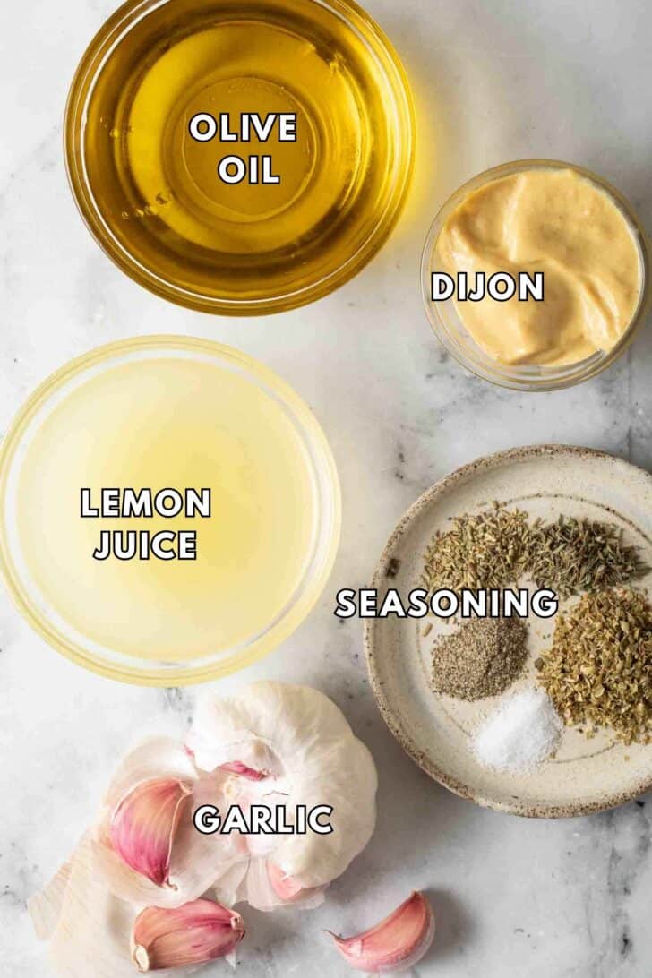 Lemon Garlic Chicken Marinade Recipe Clear glass bowls filled with lemon juice, olive oil, Dijon mustard, garlic cloves and seasoning for lemon garlic chicken marinade recipe.