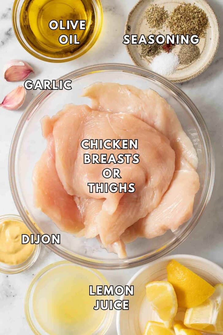 Grilled Lemon Chicken Recipe Clear glass bowls filled with raw chicken breasts, olive oil, Dijon mustard and lemon juice for Grilled Lemon Chicken Recipe.