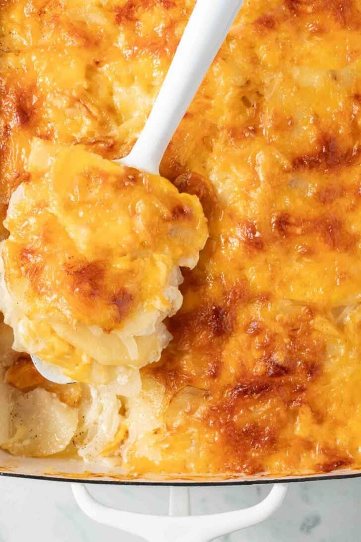 Cheesy Au Gratin Potatoes Cheesy Au Gratin Potatoes in a white baking dish with a serving spoon.