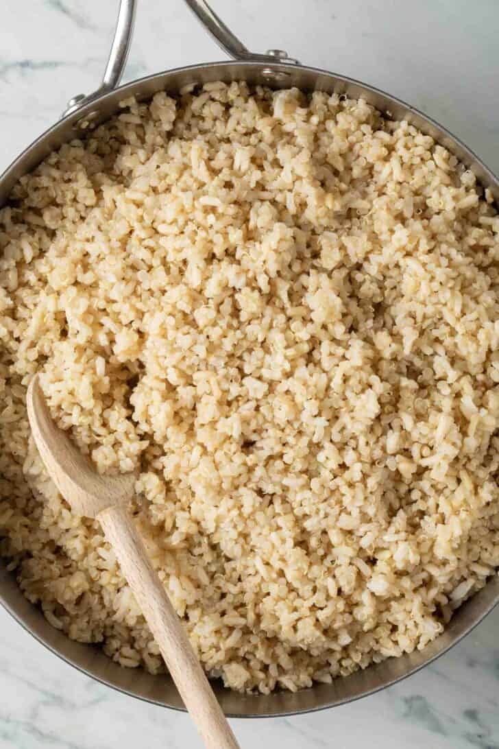 Quinoa and Brown Rice Cooked quinoa and rice in a skillet with a wooden spoon.