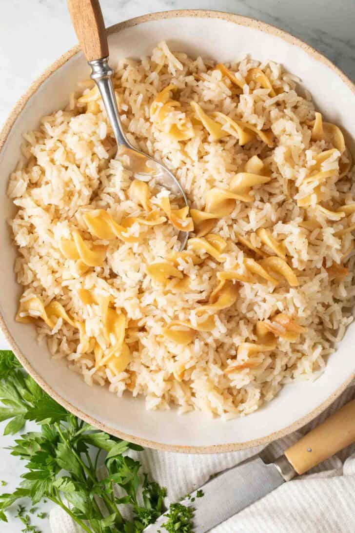 Easy Rice Pilaf Rice Pilaf in a bowl with a serving spoon.