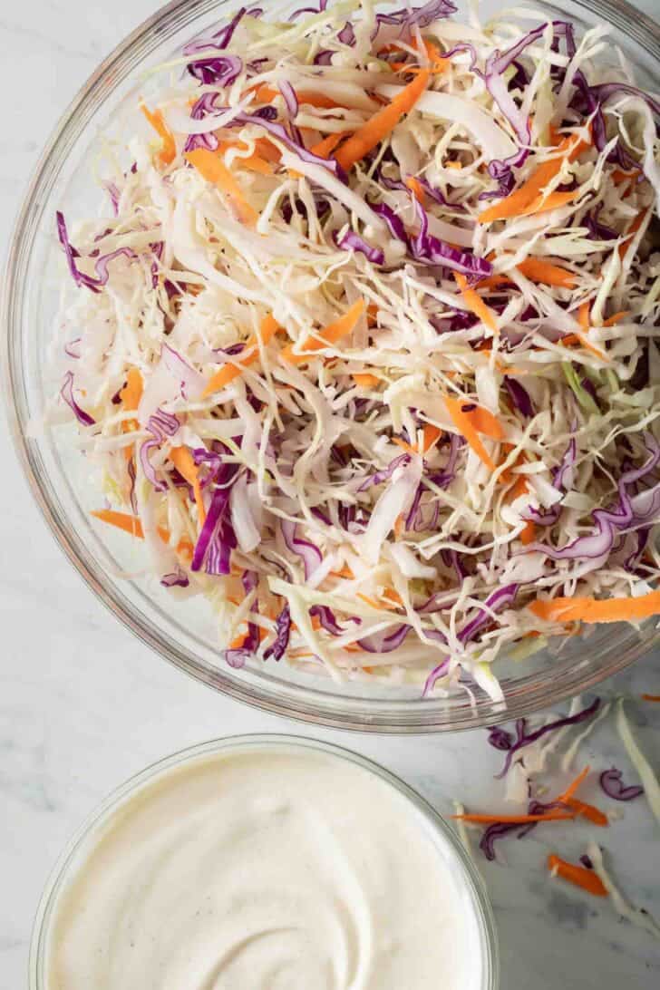 Easy Coleslaw Shredded cabbage in a clear glass bowl for basic coleslaw recipe.