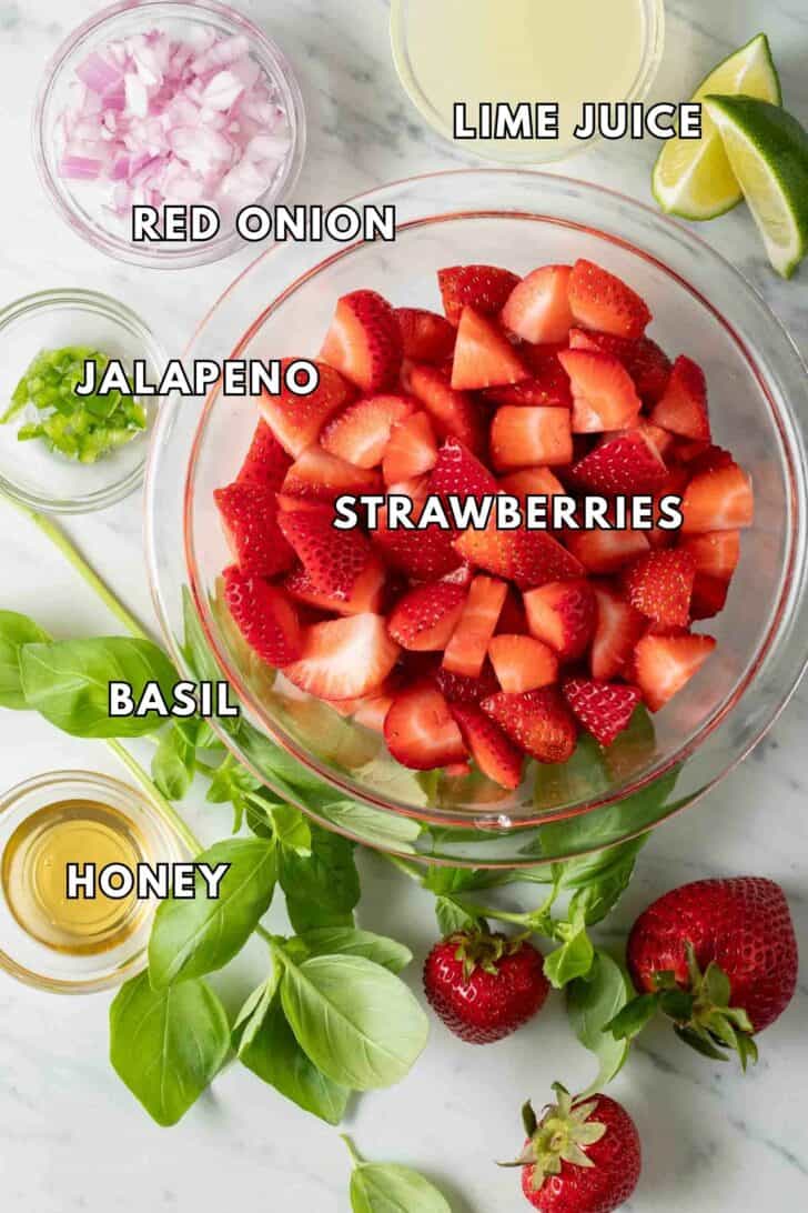 Strawberry Salsa Recipe Clear glass bowls filled with chopped strawberries, onion, jalapeno, honey and lime juice for a strawberry salsa.