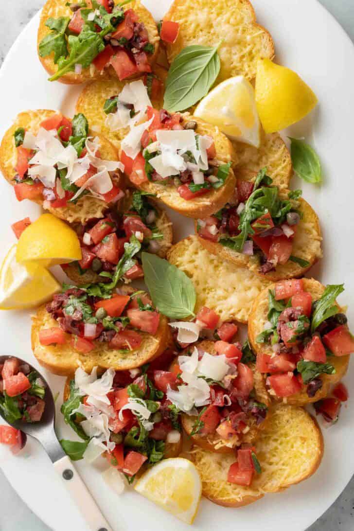 Italian Bruschetta Recipe Italian Tomato Bruschetta on a serving platter with lemon wedges.