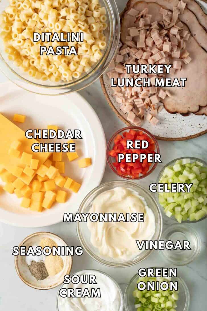 Macaroni Salad Recipe Clear glass bowls filled with ditalini pasta, mayonnaise, sour cream, celery and green onion for a macaroni salad recipe.