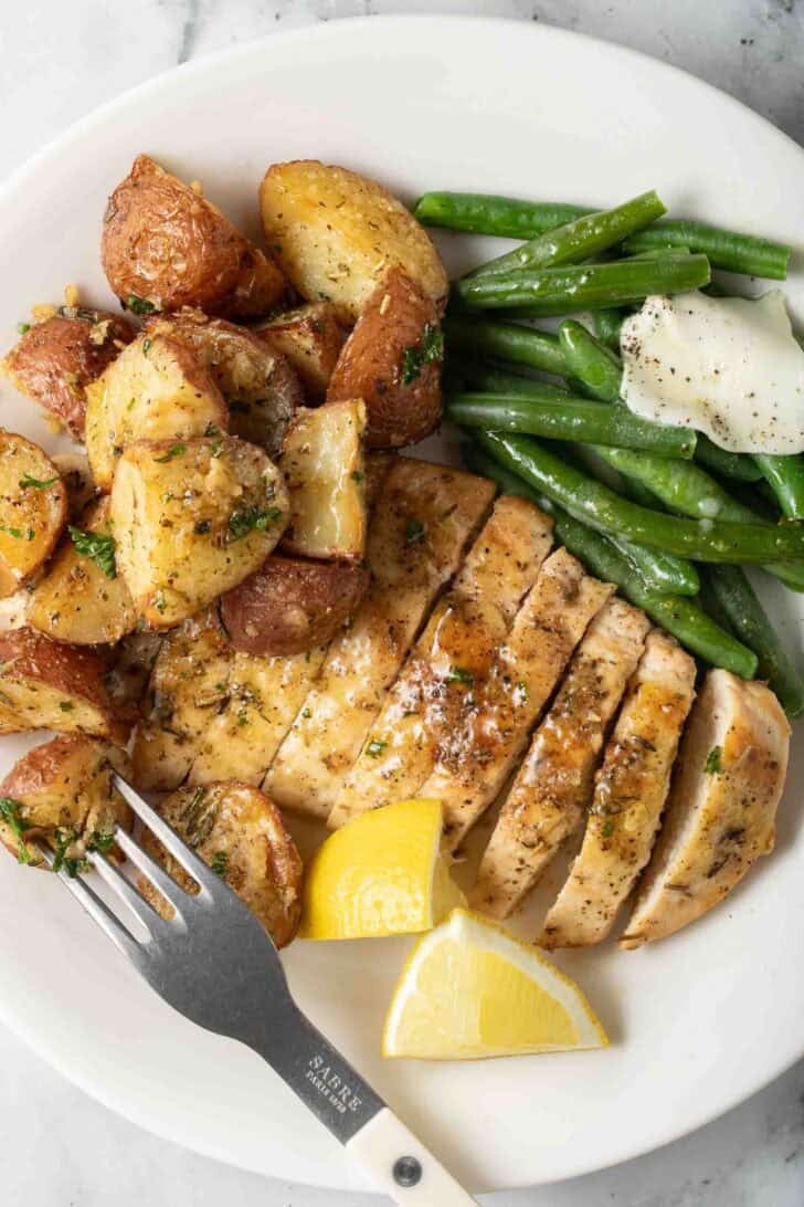 Roasted Red Potatoes Roasted Red Potatoes on a plate with grilled chicken and string beans.