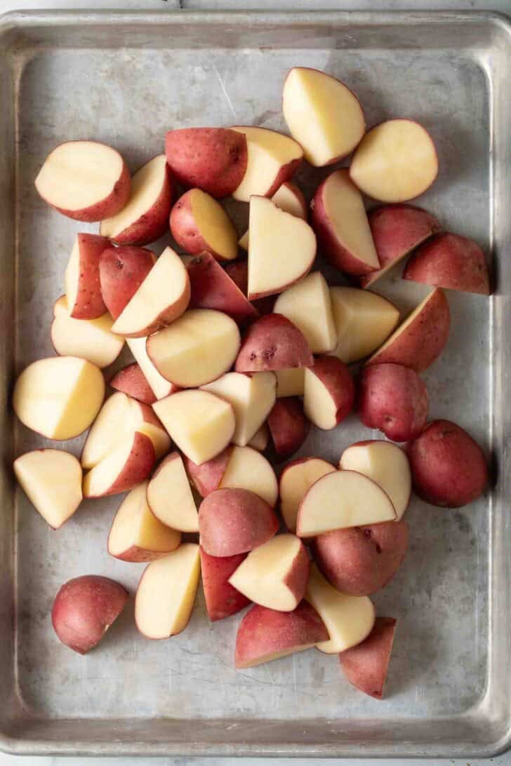 How To Make Roasted Red Potatoes Red potatoes cut in half on a baking sheet.