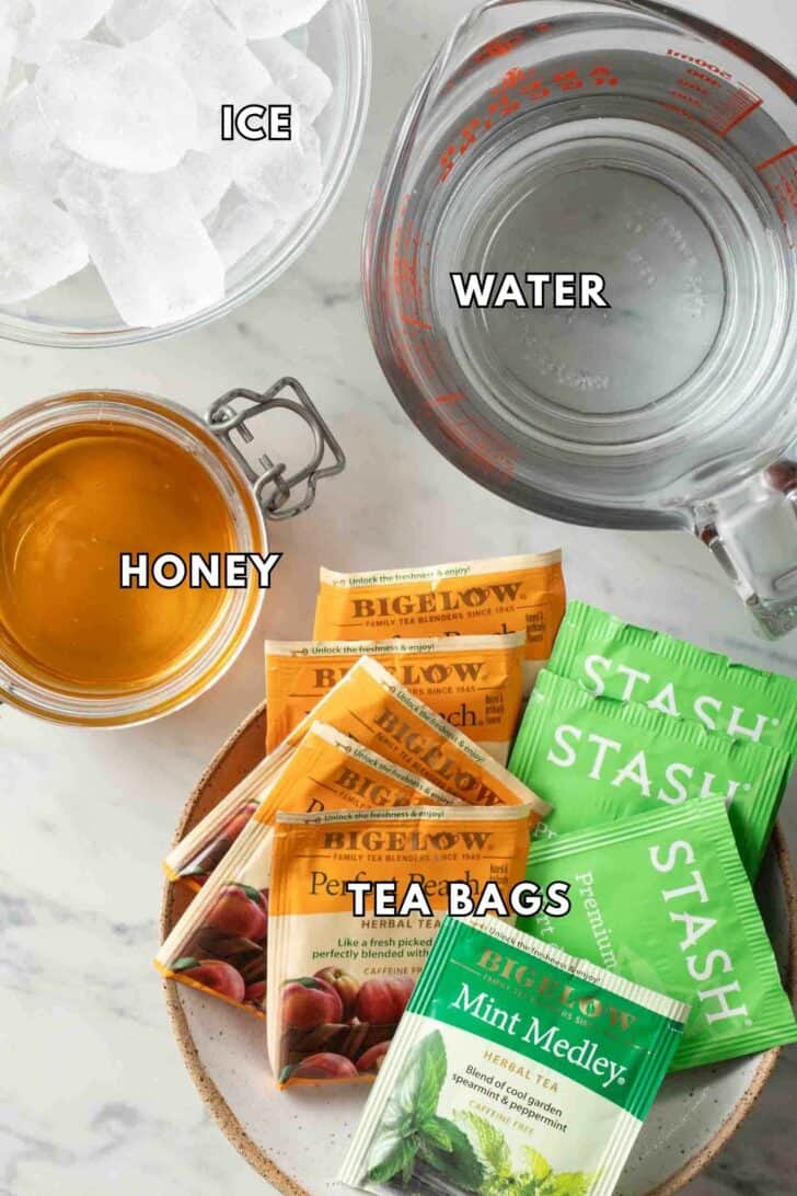 Iced Tea Recipe Clear measuring cup filled with water next to honey bags for an Iced Tea Recipe.