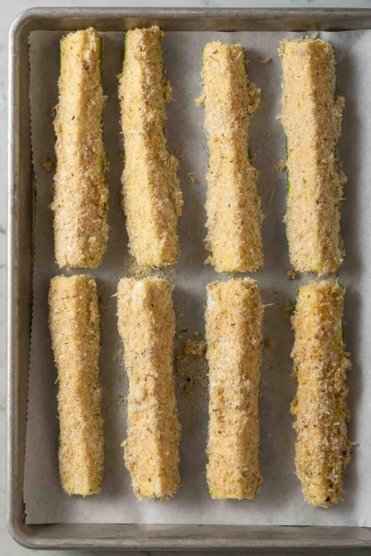 Zucchini Sticks Bread coated zucchini sticks on a baking sheet.