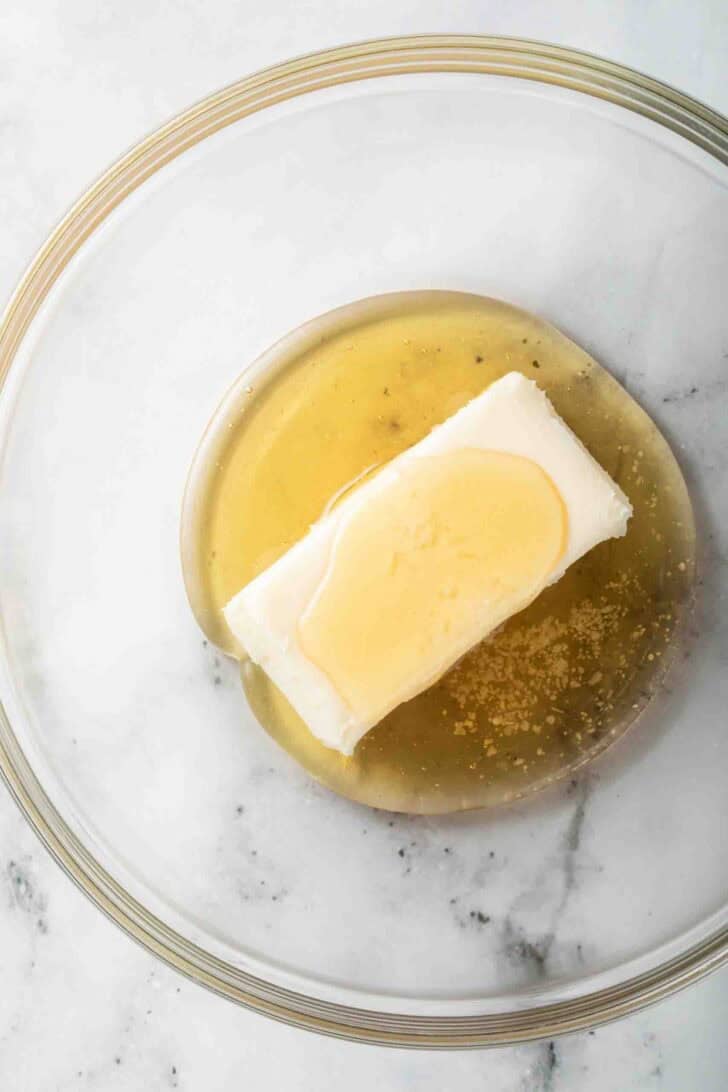 How to Make Honey Butter A stick of butter and honey in a clear glass mixing bowl for honey butter recipe.