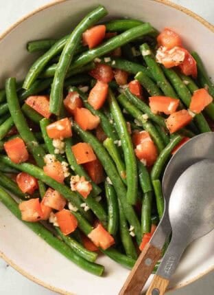 Cold Green Bean Salad in a bowl with serving spoons.