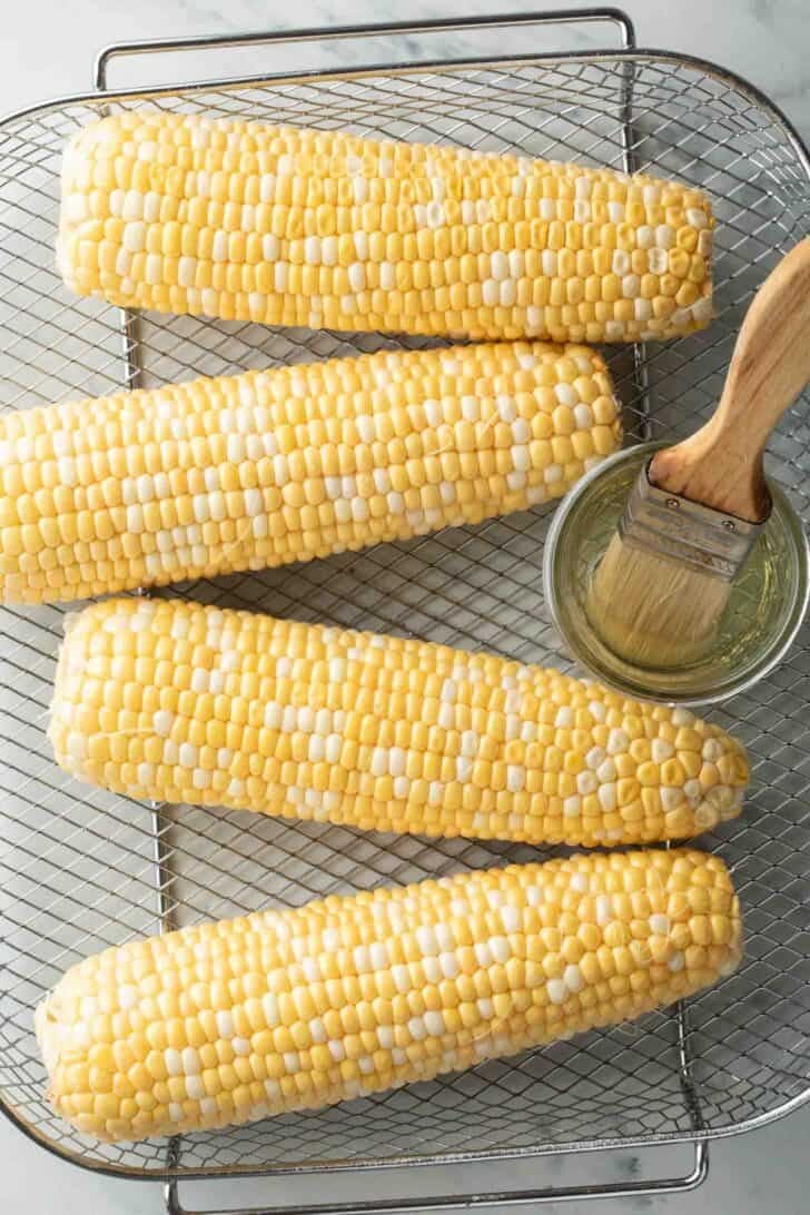 Air Fryer Corn Shucked corn in an air fryer basket for air fryer corn recipe.