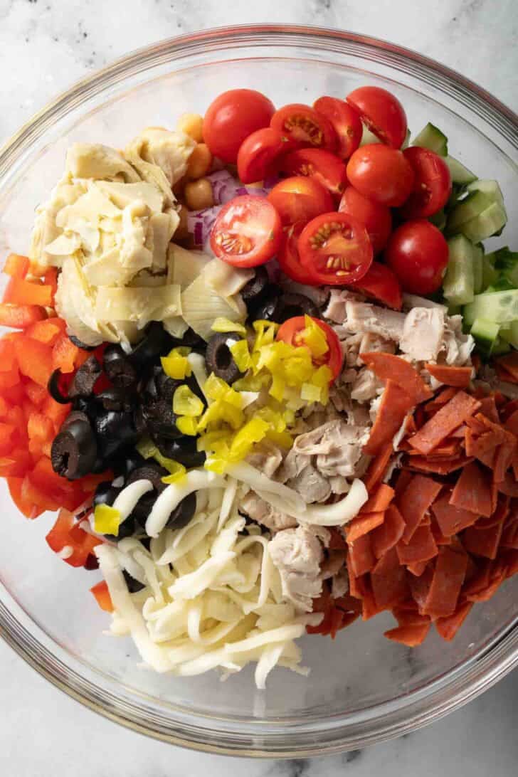 Italian Dense Bean Salad Recipe Dense Bean Salad ingredients in a clear glass bowl.