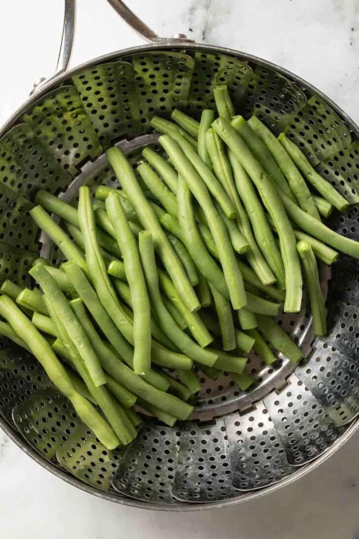 How to Make Cold Green Bean Salad Fresh green beans in a steamer basket.