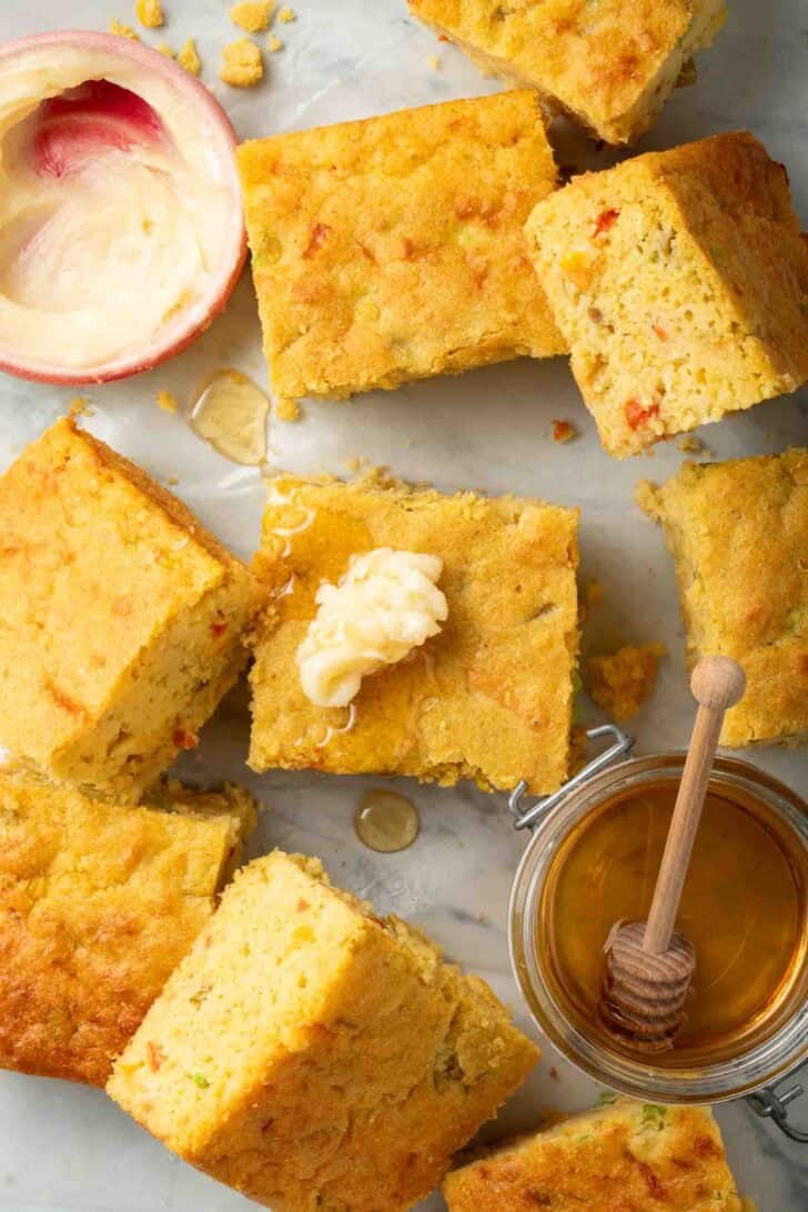 Cornbread with Creamed Corn Mexican Cornbread with creamed corn cut into squares next to a bowl of honey butter.